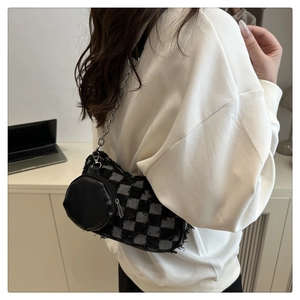 Close-up of checkerboard denim crescent bag with tassel details and chain strap