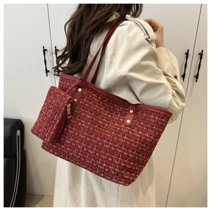 Détail d'un sac cabas en tweed rouge avec pochette assortie et rivets dorés sur modèle