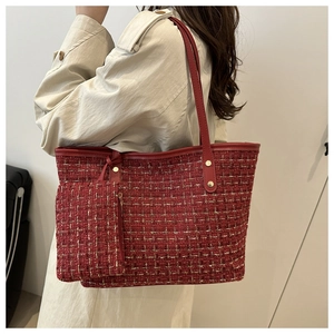 Gros plan d'un sac cabas en tweed rouge avec bordure en cuir et pochette assortie