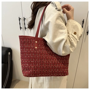 Detail of red tweed tote bag featuring gold metallic threads and leather strap handle
