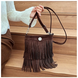 Detail of a dark brown suede crossbody bag featuring long tassels and a silver round buckle