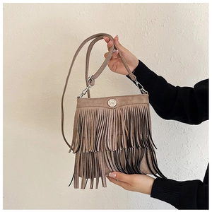 Close-up of bohemian tassel crossbody bag in light brown faux suede with metal buckle
