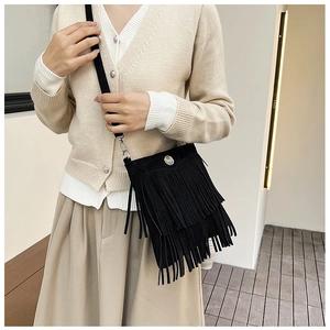 Detail of black suede shoulder bag featuring layered fringe tassels and a metal buckle