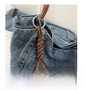 Close-up of woven rope charm attached with silver metal ring on blue denim bag fabric
