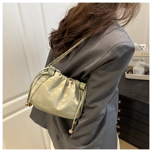 Détail du sac seau vert clair plissé avec bandoulière chaîne dorée et cordon de serrage