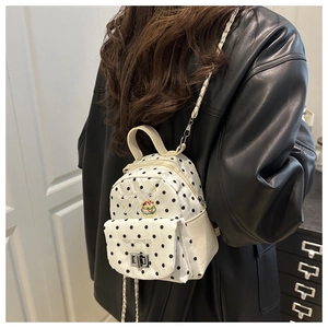 Détail d'un mini sac à dos blanc à pois avec bandoulière chaîne sur veste en cuir