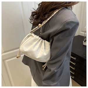 Détail du sac seau plissé blanc avec bandoulière en chaîne dorée porté par un mannequin