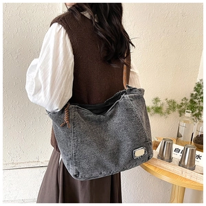 Detail of vintage gray denim tote bag featuring woven leather drawstring and metal tag