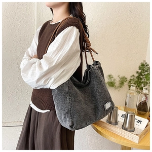 Close-up of deep gray denim tote bag featuring durable brown rope handles and metal detail