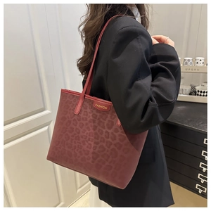Detail view of burgundy leopard print tote bag with thin straps on a model shoulder