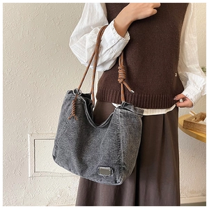 Detail of gray washed denim tote bag with rope strap and metal ring attachments