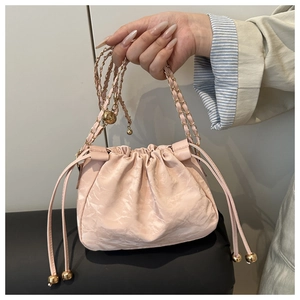 Detail of light pink bucket bag with pleated texture and gold chain strap handle