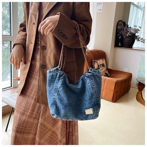 Vintage blue denim tote bag detail featuring brown woven rope straps and frayed patch design