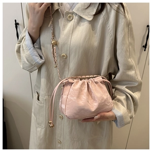 Détail du sac seau rose clair à cordon avec chaîne dorée et bille de réglage en métal