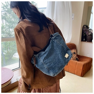 Detail of vintage blue denim tote bag with side metal plate and brown woven zipper puller