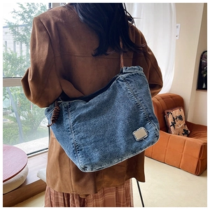 Detail of large denim tote bag featuring heavy washed fabric and braided shoulder strap
