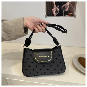 Détail de la poignée en corde tressée et du rabat en cuir du sac à main à pois noir