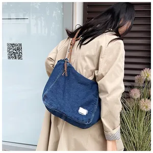 Detail of blue denim shoulder bag featuring unique knotted strap and vintage white label