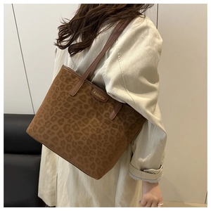 Detail of a brown leopard print tote bag with leather straps and a fashion metal plaque