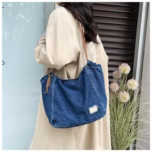 Detail showing blue denim tote bag with brown woven strap and bohemian tassel accent