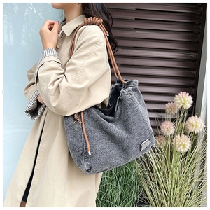 Detail of grey washed denim tote bag featuring decorative rope handles and knot accents