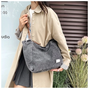 Gray washed denim tote bag featuring brown woven rope shoulder straps and side patch detail
