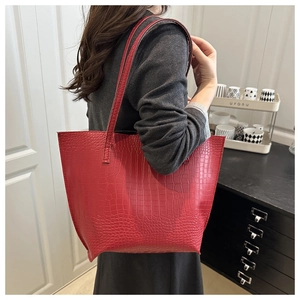Side view of red crocodile textured tote bag worn over the shoulder showing large capacity