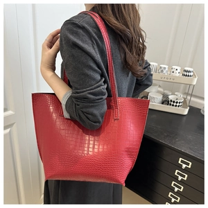 Red crocodile texture tote bag worn by a model in a modern interior setting