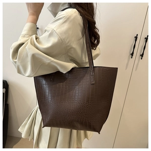Detail of dark brown tote bag with crocodile embossed texture on a female model
