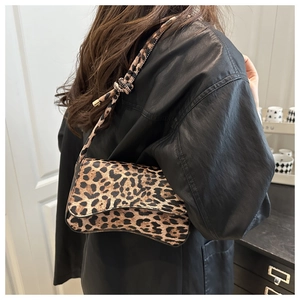 Dettaglio borsa leopardata con tracolla sottile indossata su giacca di pelle