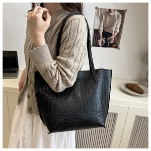 Close-up of black crocodile embossed tote bag texture and long shoulder straps