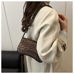 Dettaglio borsa leopardata in ecopelle con base a sella e cinturino sottile con nodo decorativo