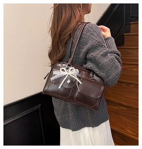 Détail du sac Boston marron avec nœud en dentelle, perles et pendentif en forme de cœur