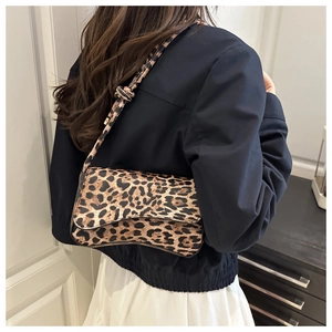 Dettaglio della borsa baguette leopardata marrone con tracolla a nodo indossata da modella