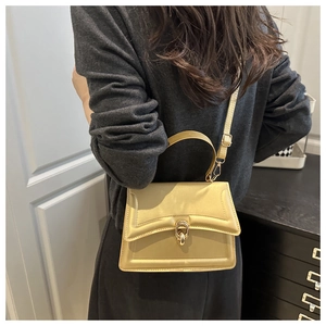 Detail der champagner-goldenen Handtasche mit Metallschloss und multifunktionalem Riemen