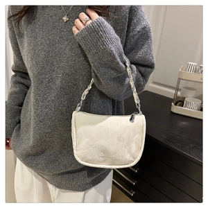 Détail du sac matelassé crème avec texture marbrée et bandoulière chaîne argentée