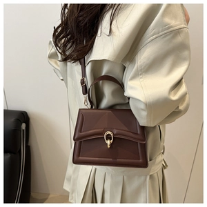 Brown textured leather crossbody bag with gold buckle on a model in a beige trench coat