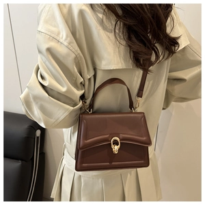 Braune Lederhandtasche mit Gold-Schnalle an Model in beigem Trenchcoat präsentiert