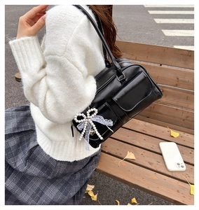 Détail du sac en cuir brillant noir avec nœud en perles et ruban dentelle au décor d'automne