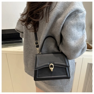 Detail of elegant black leather handbag with golden ring buckle and chic quilted stitching
