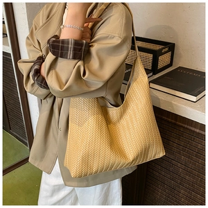 Detailed view of beige woven bucket bag with elegant V-texture on female model