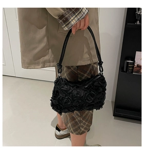 Detail of 3D fabric rose textures and knotted shoulder strap on black evening bag