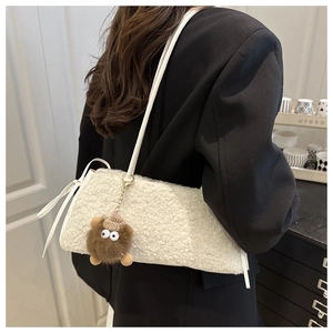 Detailed back view of a plush white teddy tote bag with brown monster charm and leather strap