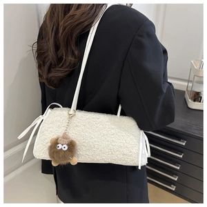 Vue détaillée d'un sac fourre-tout en peluche blanche avec un porte-clé monstre