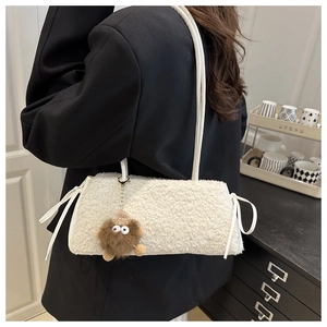 Detailed texture of white plush tote bag with brown monster pendant and bow charm