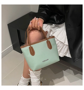 Detail of mint green lychee pattern handbag with brown cylindrical handle and metal logo