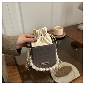 Detailed view of leopard print bucket bag with pearl handle and golden chain strap
