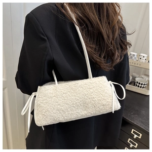 Detail view of plush white fleece shoulder bag with stylish bow tassels on black suit