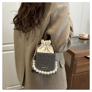 Detail of leopard print suede crossbody bag with pearl chain and drawstring closure