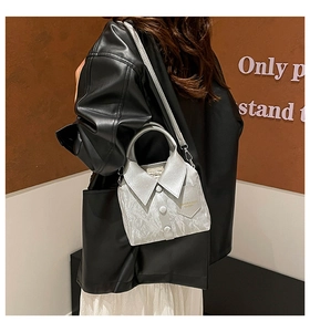 Detail of silver shirt-shaped handbag showing folded collar and button accents